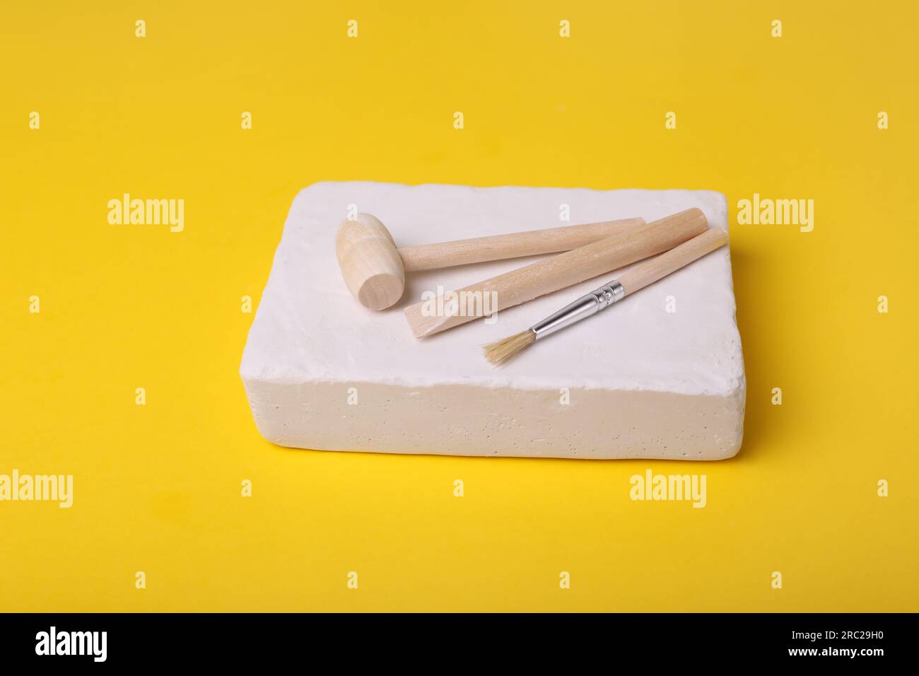 Jouet éducatif pour le développement de la motricité. Kit d'excavation (plâtre, outils d'excavation et brosse) sur fond jaune Banque D'Images