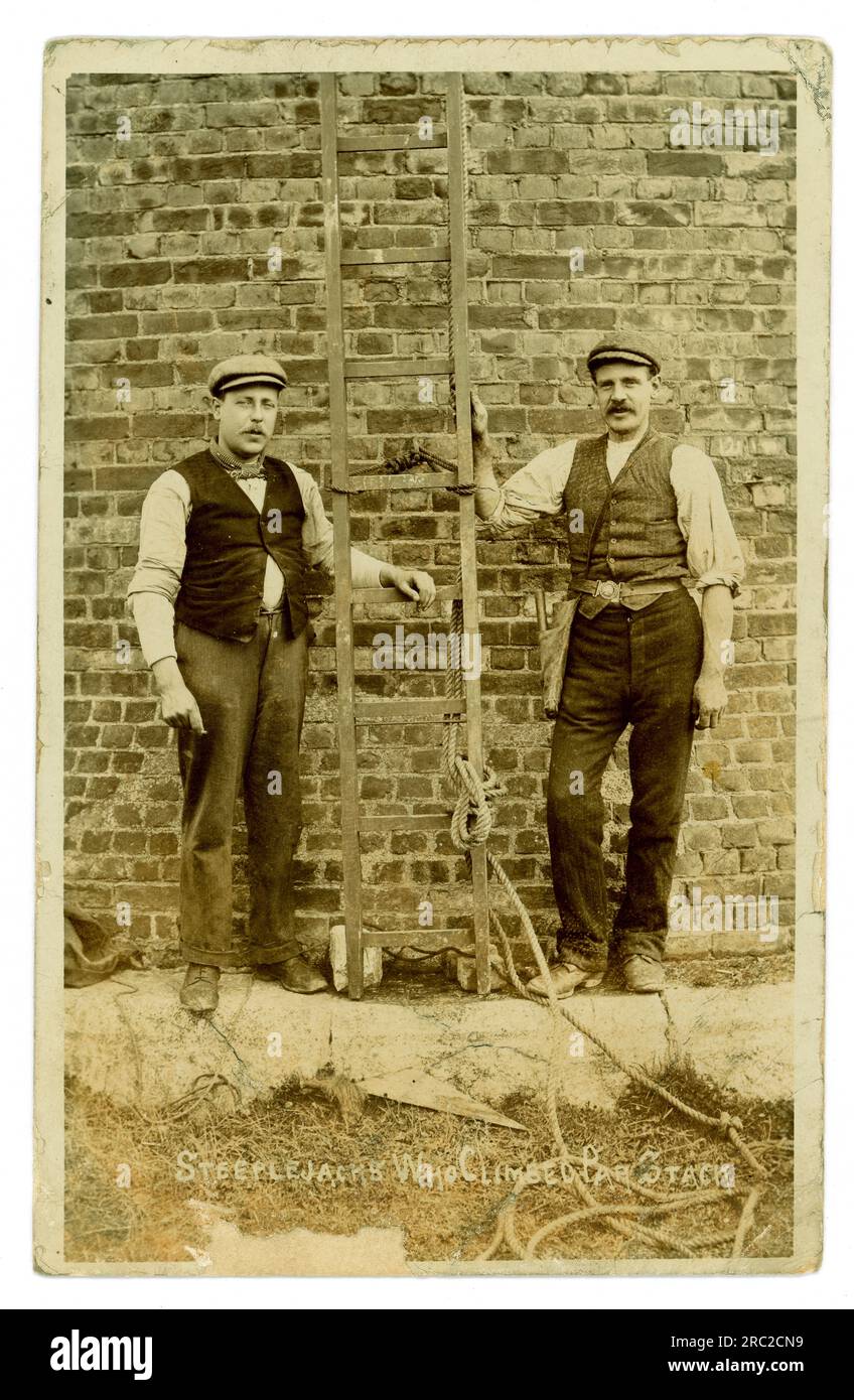 Carte postale originale du début des années 1900 de 2 braves steeplejacks par village qui ont grimpé par stack, Cornwall, South West England, Royaume-Uni Par Stack, la cheminée d'une fonderie de plomb, était la plus haute des Cornouailles. Il s'agissait probablement de steeplejacks qui contribuèrent à démolir la cheminée le 23 août 1907. La pile se trouvait à l'extrémité du port de par Road. De l'atelier de S. Dalby-Smith St Blazey. Banque D'Images