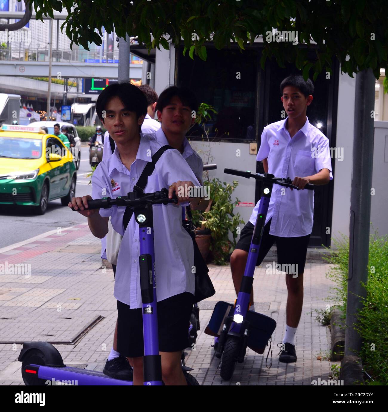 Adolescents garçons, âgés de 14-16 ans, monter E - vélos sur le trottoir dans le centre de Bangkok, Thaïlande, Asie du Sud-est. Cela pose un risque pour les piétons et la question de savoir si cela doit être autorisé fait l'objet d'un débat dans de nombreux pays. Banque D'Images