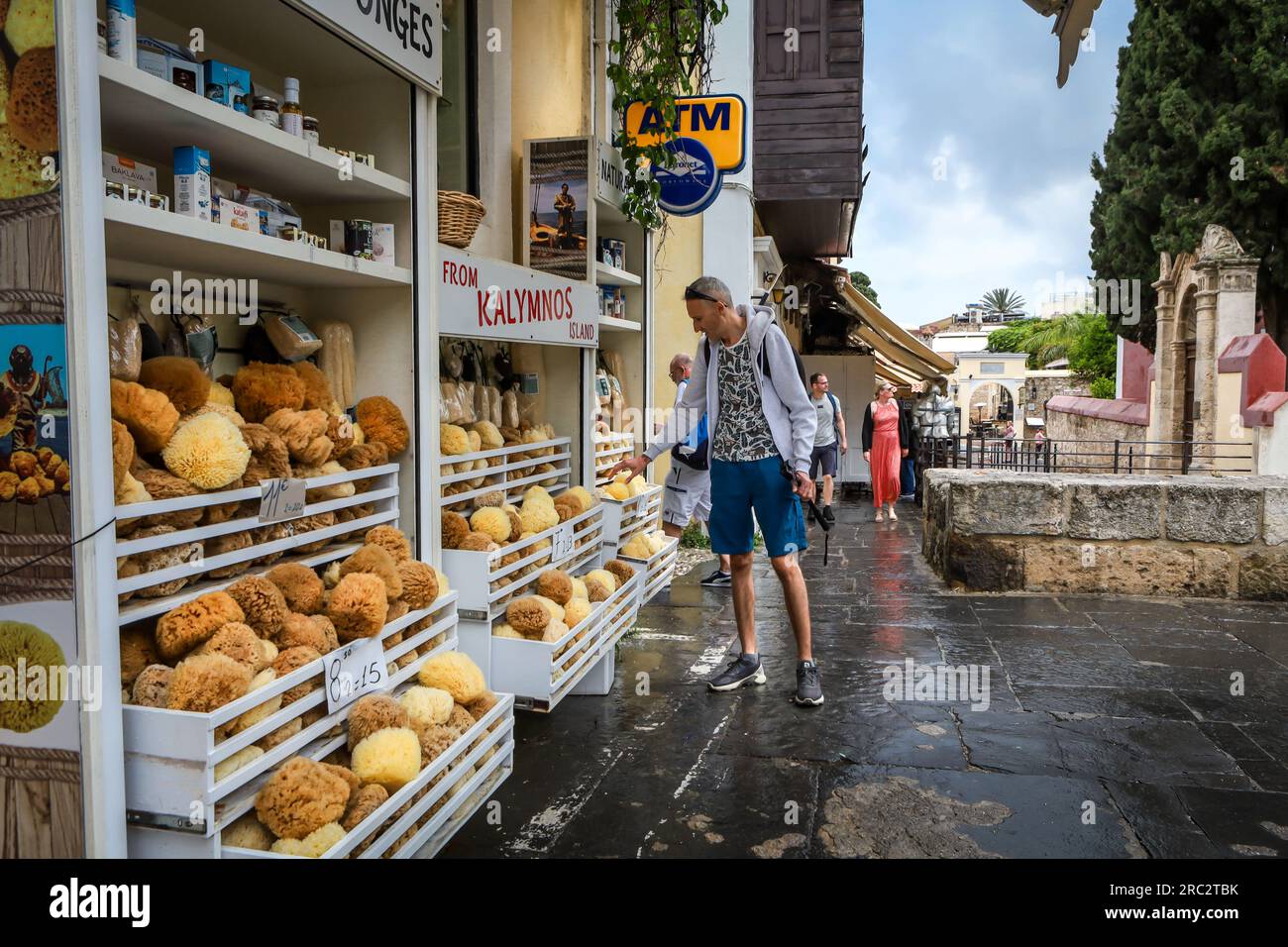 Rhodes, Grèce - 27 mai 2023 : une boutique de cadeaux avec des éponges grecques naturelles de Kalymnos. Un client touristique à l'extérieur du magasin. Banque D'Images