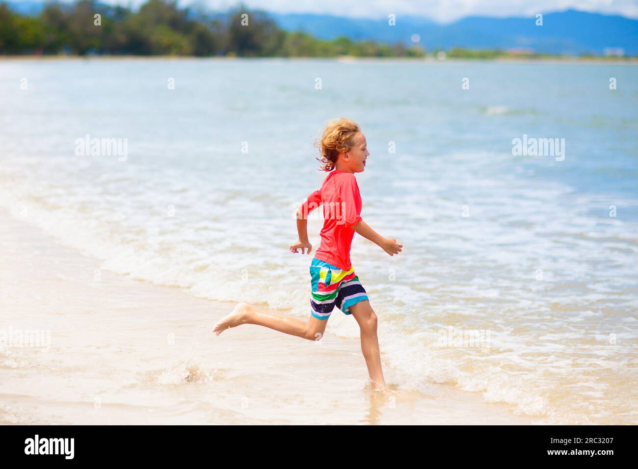 Enfant jouant sur la plage tropicale. Groupe de garçons courant au bord de la mer. Vacances d'été en famille. Voyage et camping avec les enfants. Banque D'Images