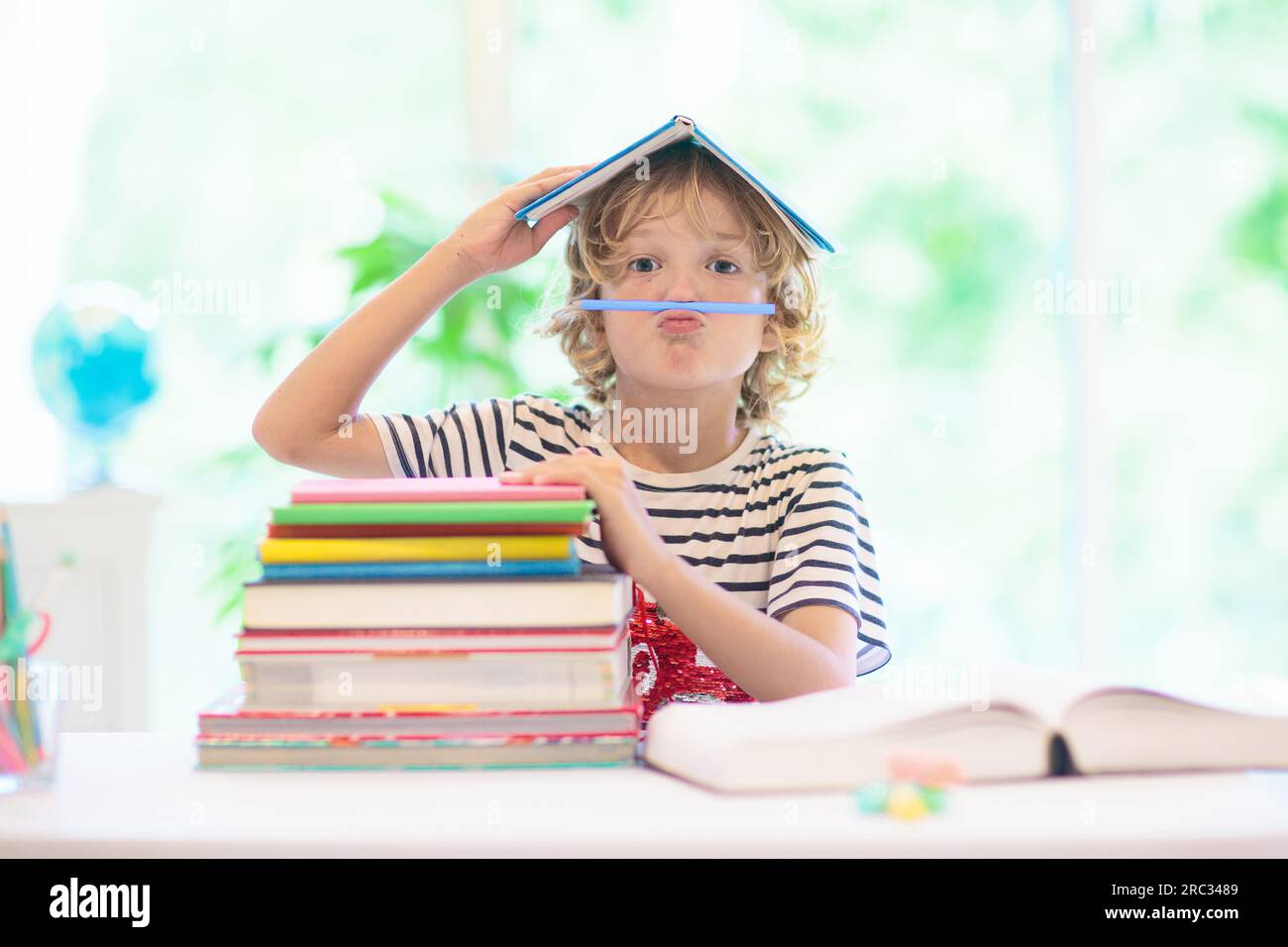 Enfant faisant ses devoirs à la maison. Petit enfant avec des livres colorés lisant et faisant des exercices mathématiques. Les enfants étudient et apprennent. Écolier avec écriture de livres Banque D'Images