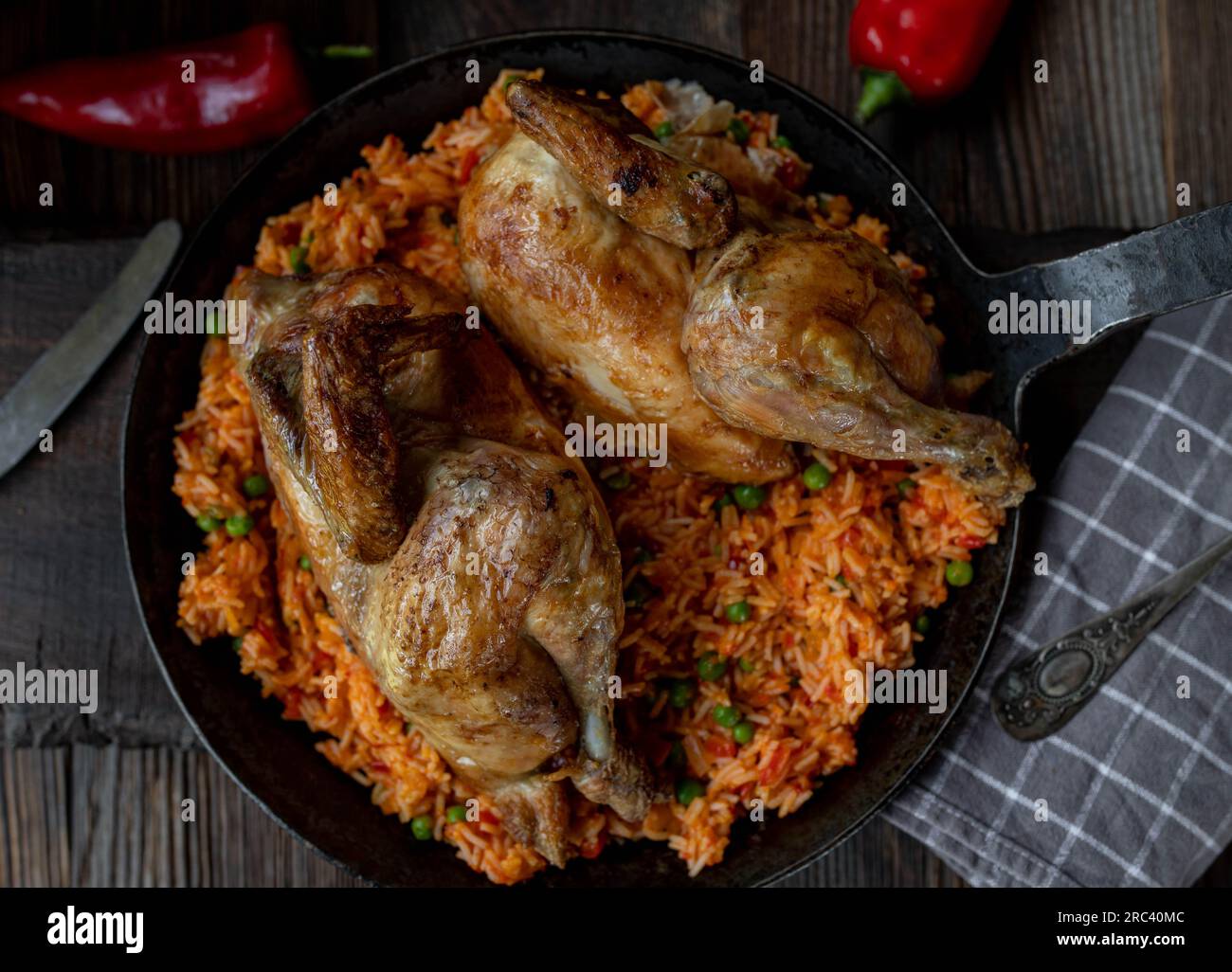 Poulet cuit au four avec du riz djuvec serbe et des légumes dans une poêle sur fond de bois Banque D'Images