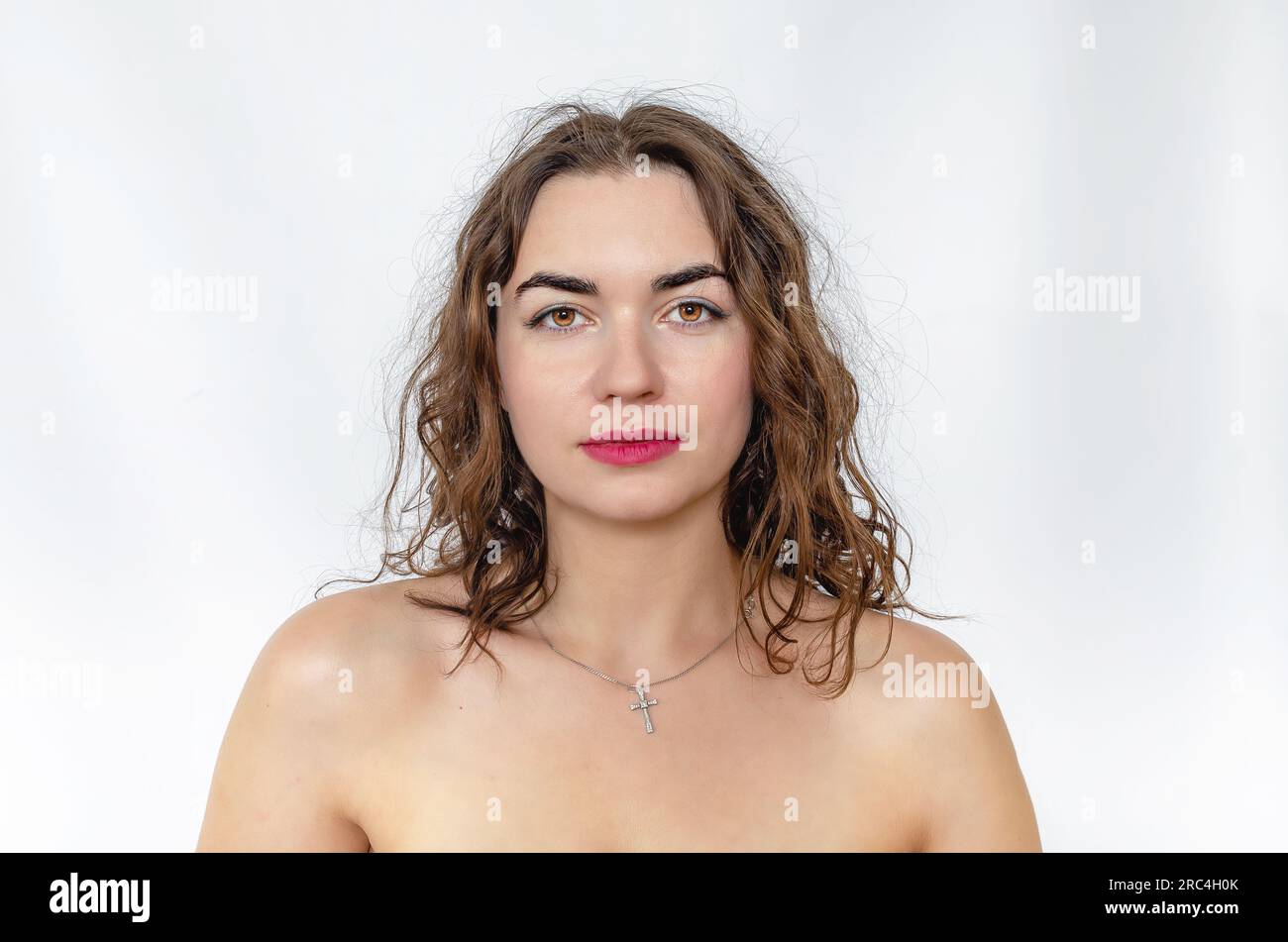 Femme aux épaules nues. Cheveux foncés ondulés, sourcils noirs, yeux bruns. Banque D'Images