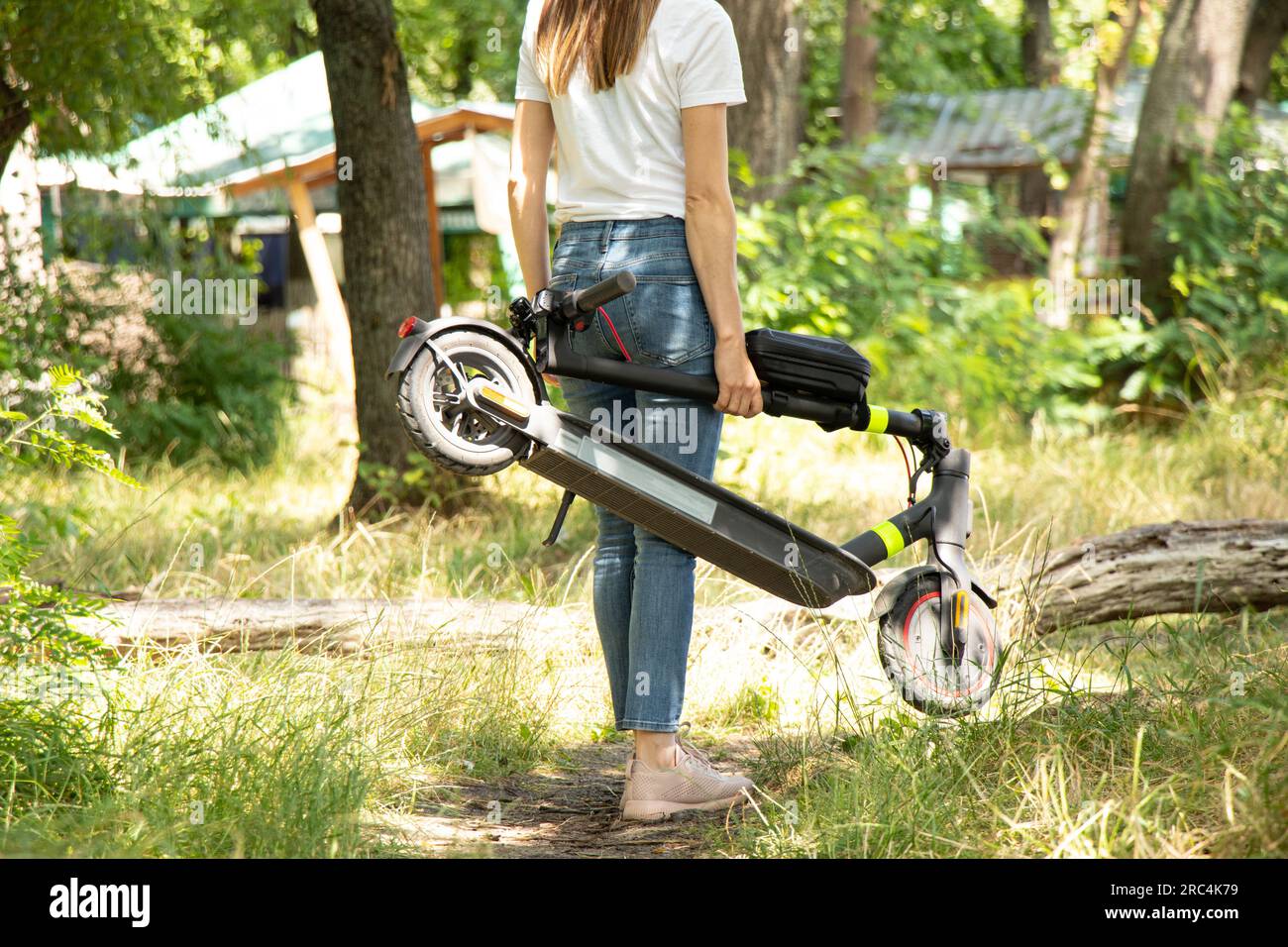 Une fille tient un scooter électrique dans ses mains dans les parcs en Ukraine en été, le transport électrique urbain Banque D'Images