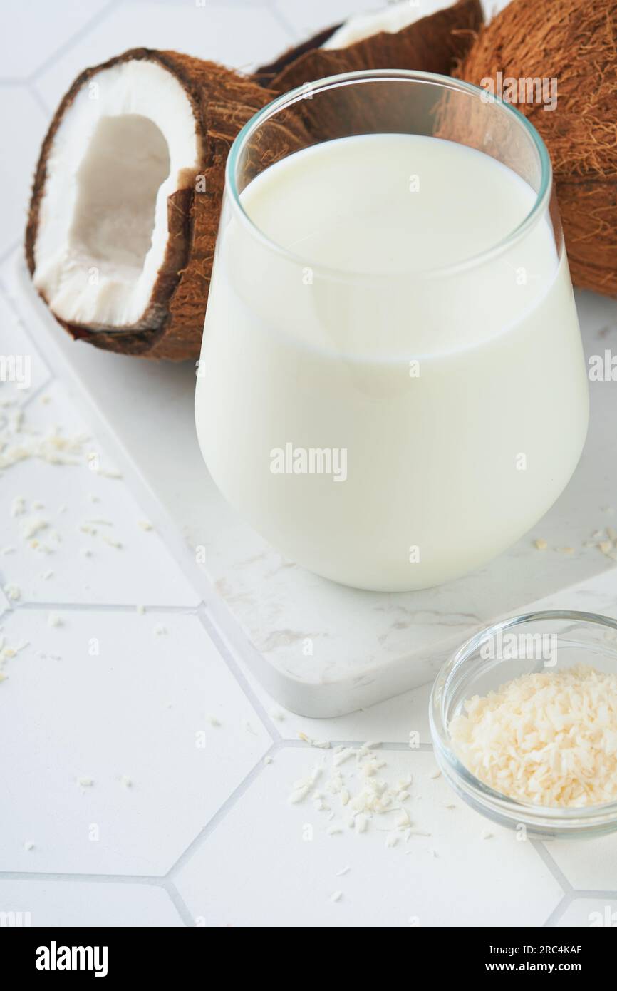 Verre de lait de coco et noix de coco se ferment sur un fond blanc avec espace pour le texte. Concept de lait végétalien noix de coco non laitier ou lait sans produits laitiers. Sain Banque D'Images