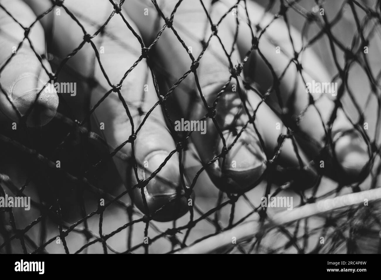 La main d'un homme dans une photo en noir et blanc en gros plan de la grille Banque D'Images