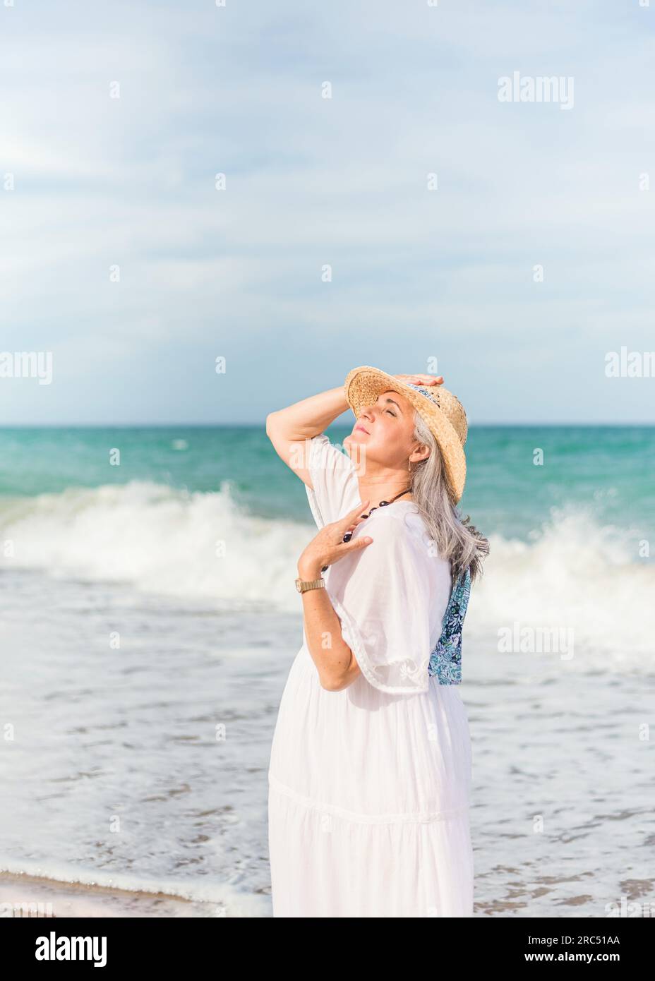 Vue laterale de la vieille dame en robe blanche et chapeau de paille penchant la tete en arriere tout en profitant de sunbeam sur la cote Photo Stock Alamy