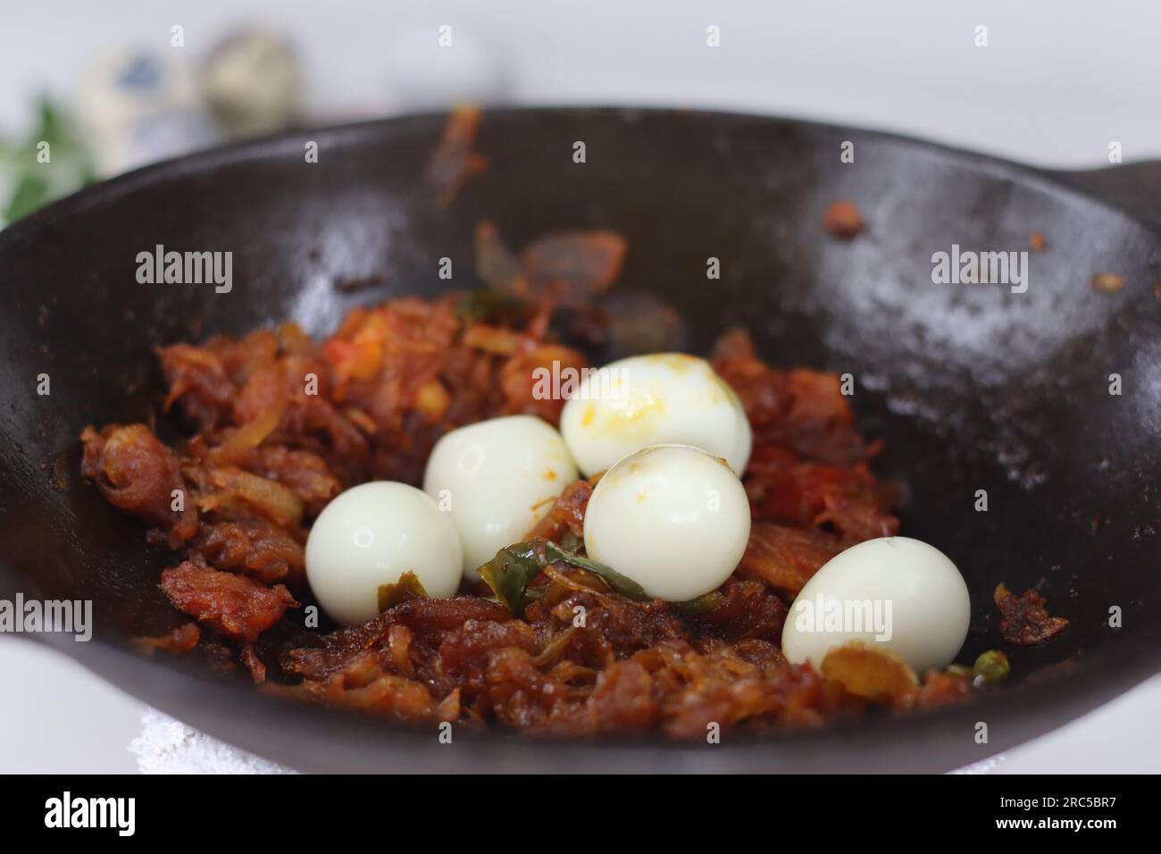 Rôti d'oeuf de caille cuit style kerala servi dans une poêle en fonte. Il est fait en mélangeant l'œuf dur avec l'oignon rouge, épicé et caramélisé de tomate masala g Banque D'Images