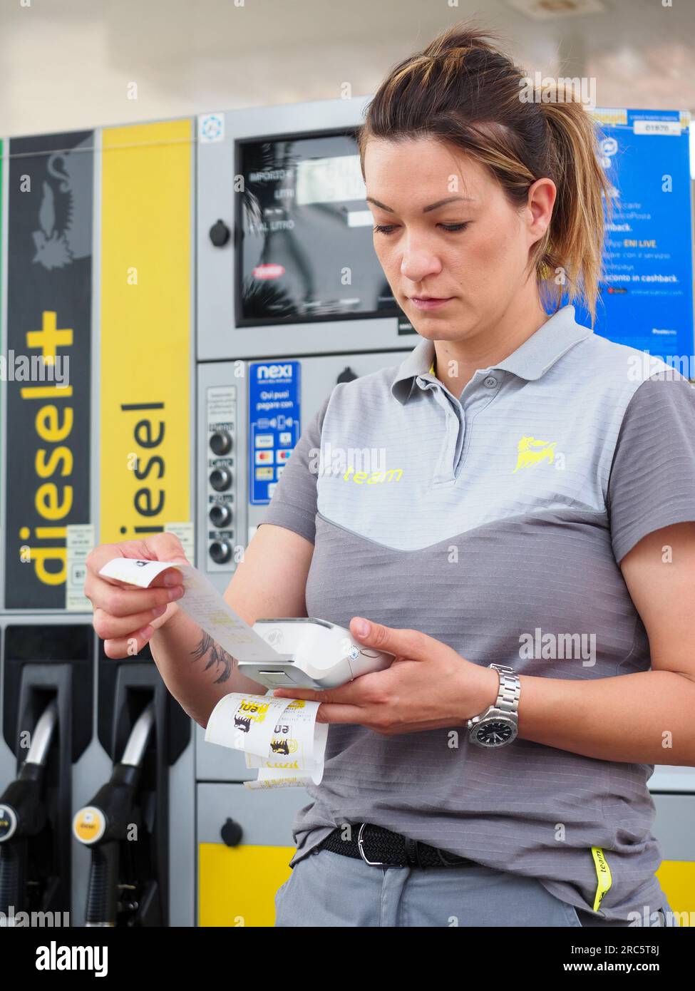 Cremona, Italie - juillet 3 2023 femme préposée à la station-service prenant les paiements par carte de crédit des clients à l'extérieur près des pompes à essence Banque D'Images