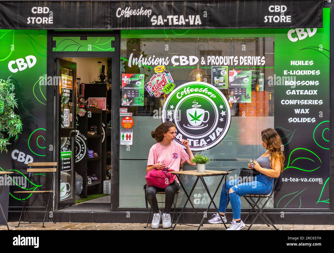 Deux jeunes femmes se sont assises devant le café juridique CBD dans le centre-ville - Tours, Indre-et-Loire (37), France. Banque D'Images