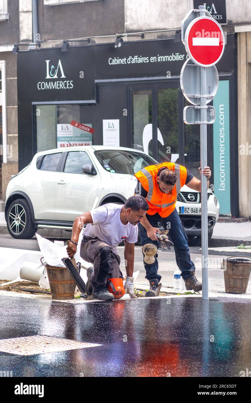 Ouvriers municipaux resurfaçage de chaussée / trottoir avec bitume chaud dans le centre-ville - Tours, Indre-et-Loire (37), France. Banque D'Images