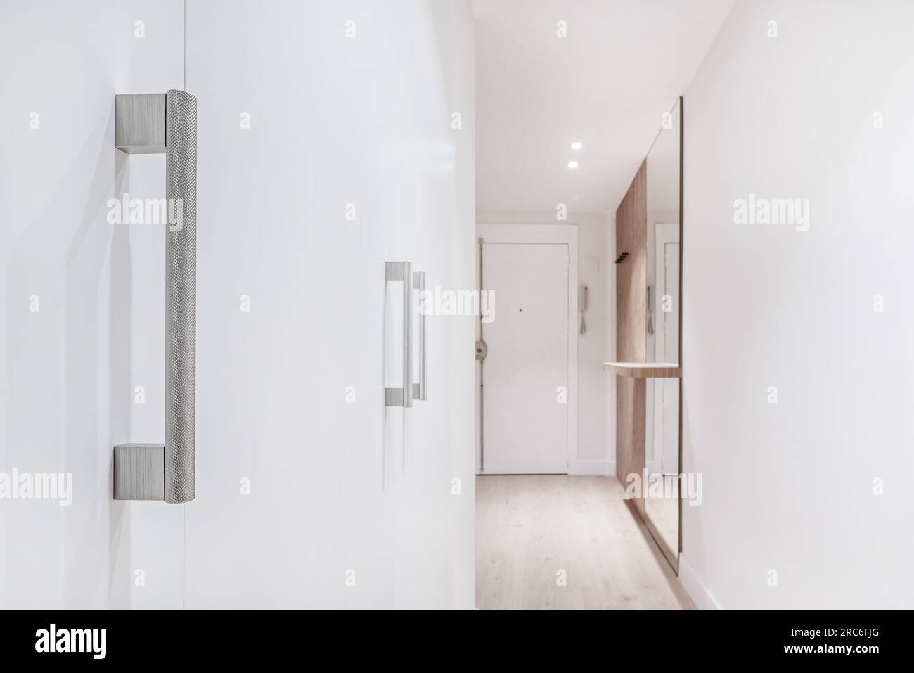 Le métal texturé tire sur les portes d'armoire en bois blanc dans un couloir de la maison Banque D'Images