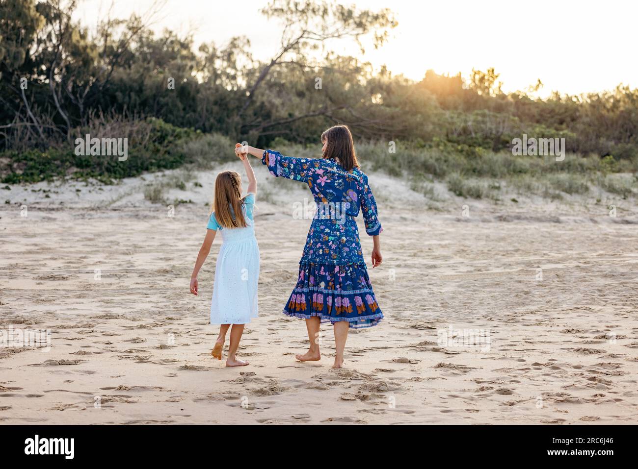 Vue arrière de mère et fille dansant sur la plage au coucher du soleil. Vacances en famille sur la Gold Coast Banque D'Images