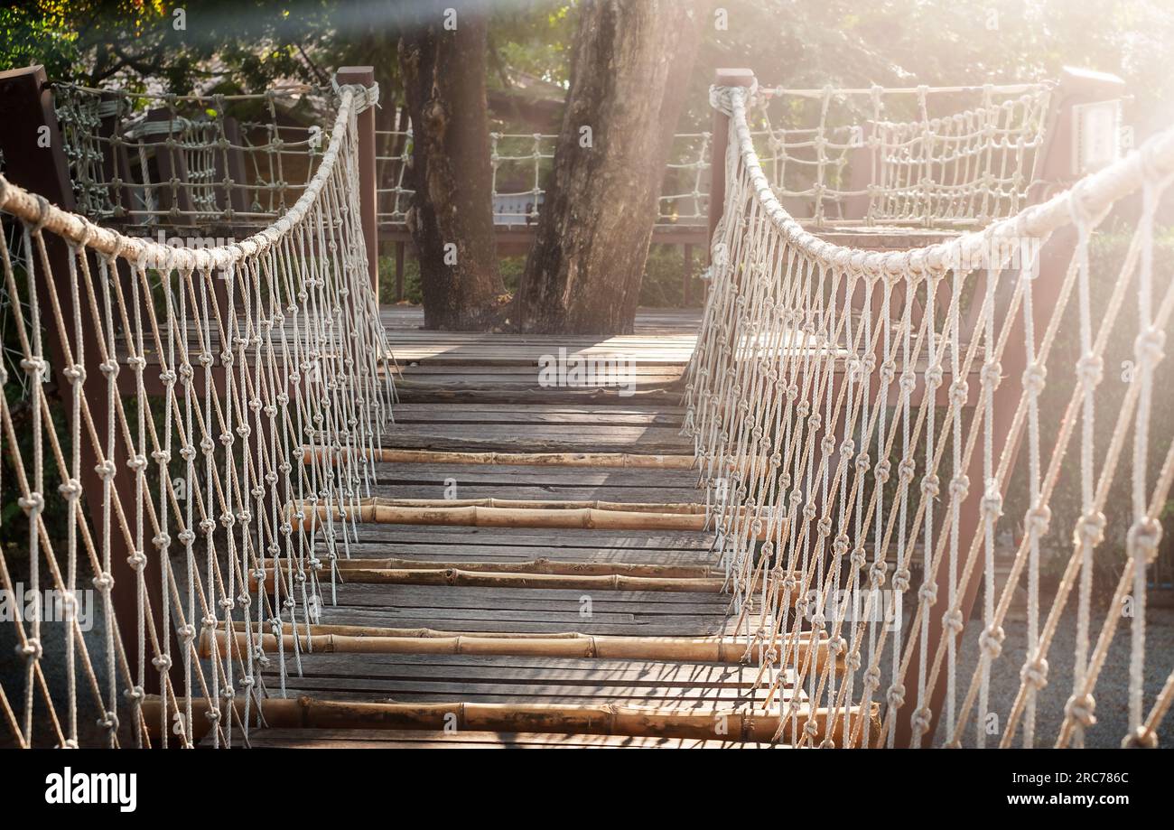 Pont articulé en bois dans le parc au coucher du soleil Banque D'Images