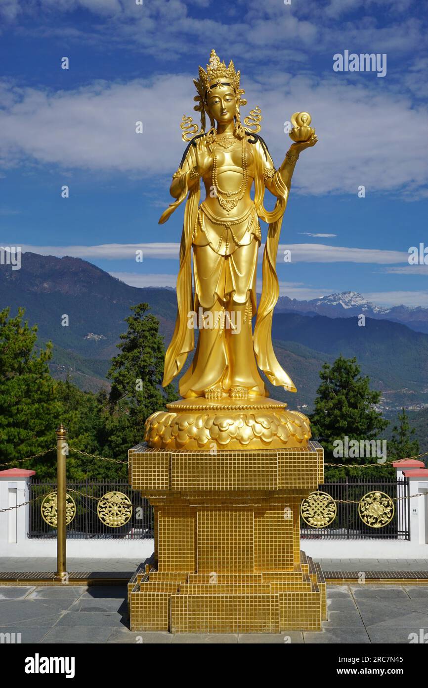 Statue dorée de la déesse apsara sur piédestal avec ciel bleu et montagnes lointaines visibles derrière au site commémoratif de Bouddha Dordenma près de Thimphu, Bhoutan Banque D'Images