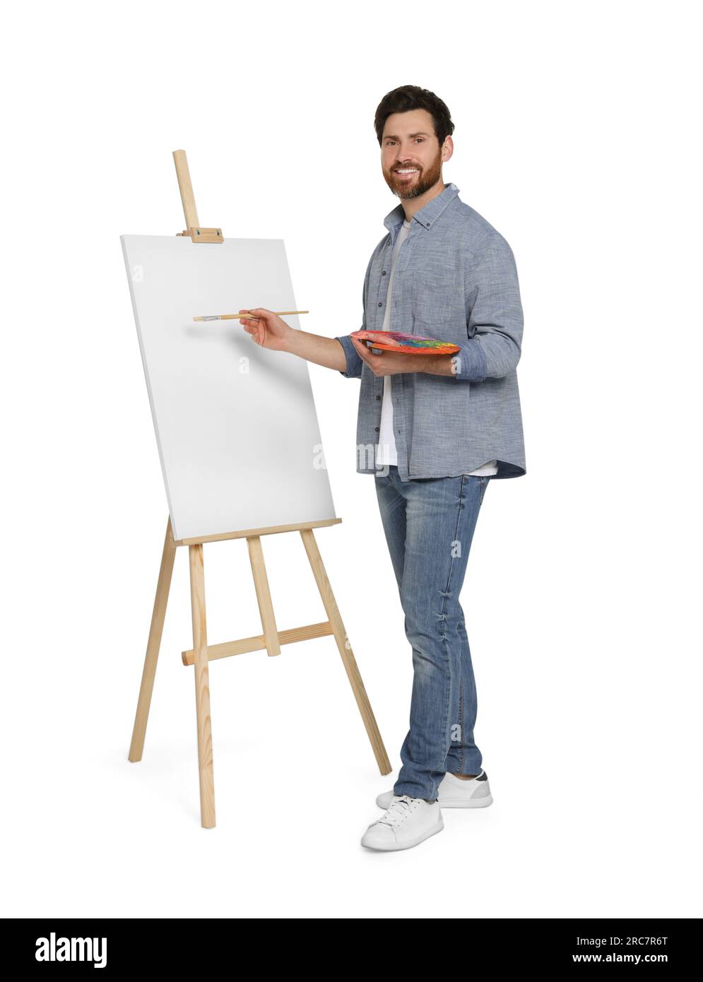 Homme heureux avec la peinture au pinceau sur fond blanc. Utiliser un chevalet pour tenir la toile Banque D'Images