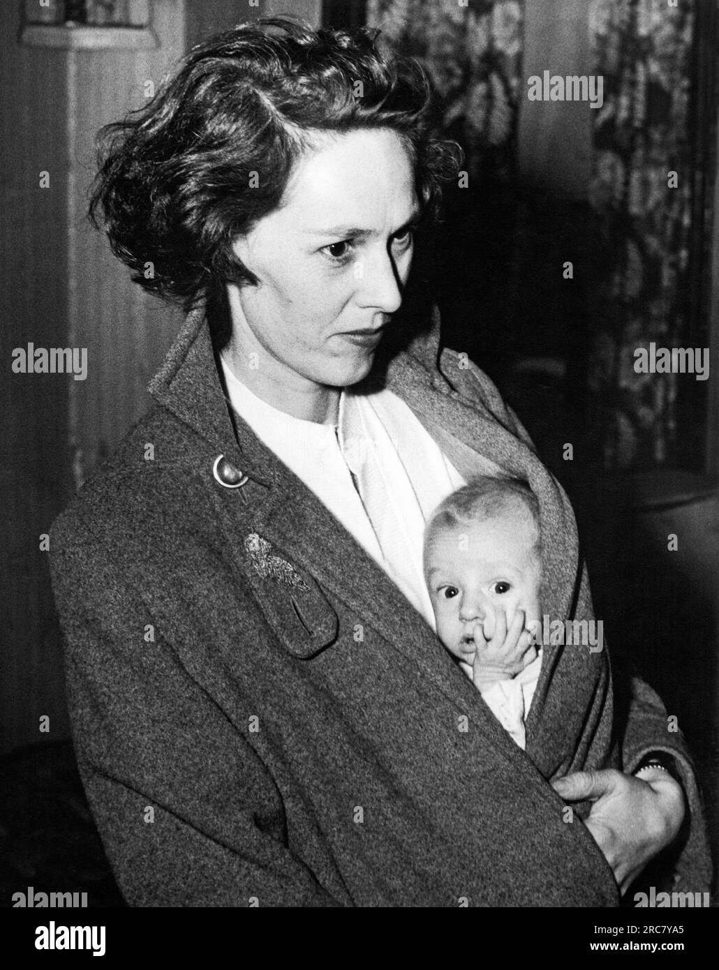 États-Unis, c 1946 un nourrisson jette un coup d'œil sous le manteau de sa mère. Banque D'Images