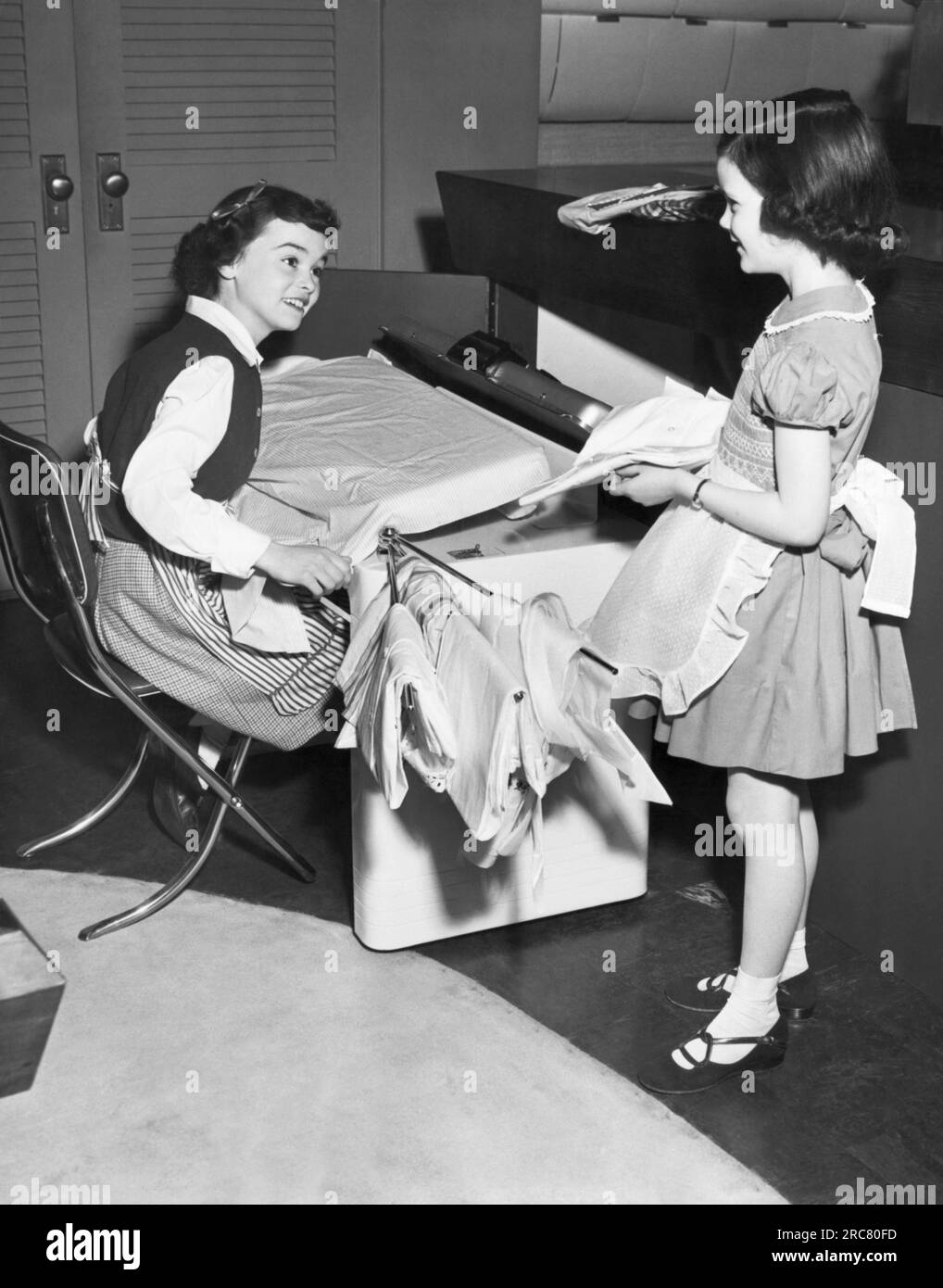 États-Unis : 1951 les enfants font du repassage comme ils aident avec les tâches ménagères. Banque D'Images