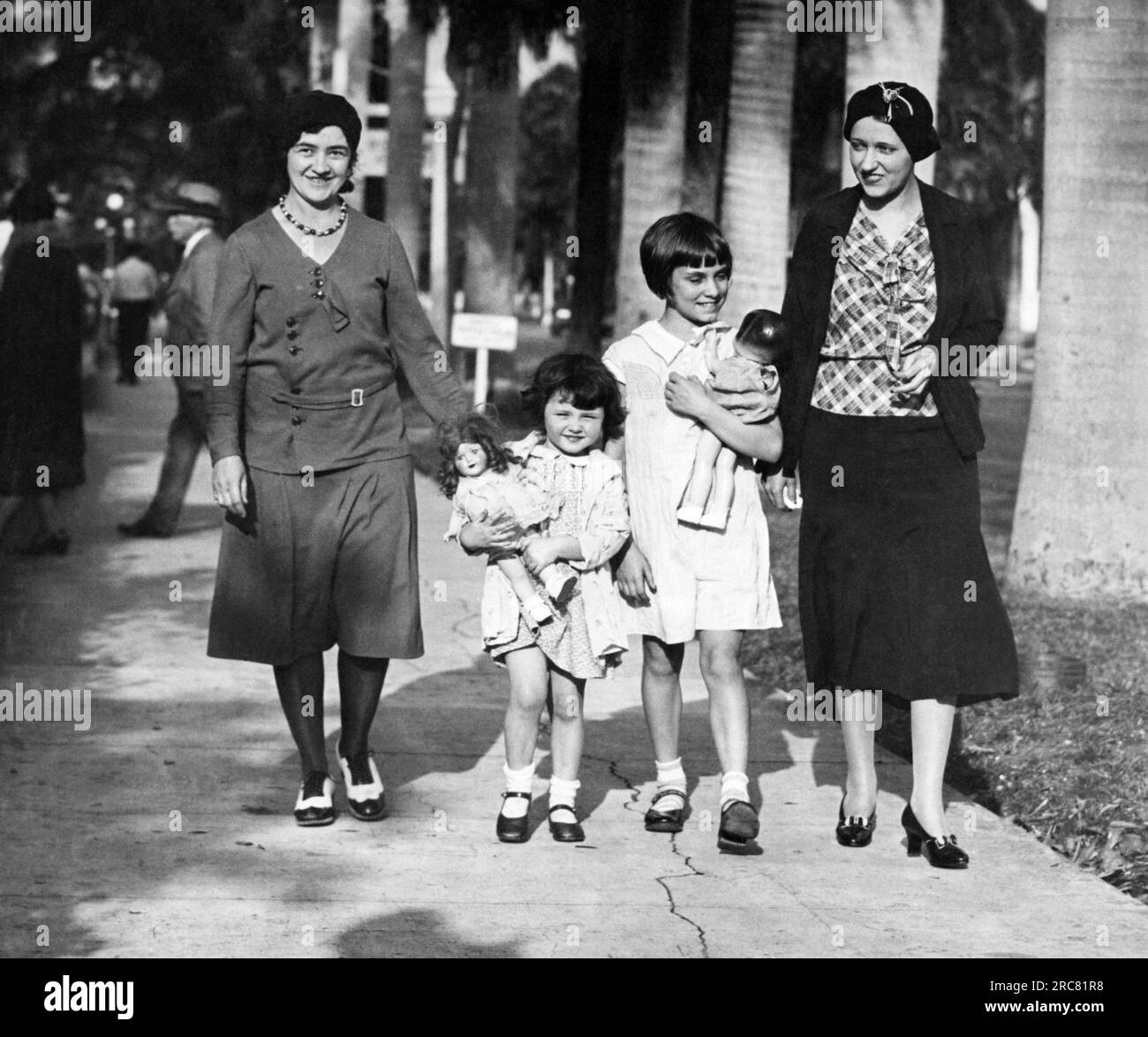 Fort Myers, Floride : 1931 deux épouses de joueurs de baseball, Mme Jimmy dykes et Mme Johnnie Hevig et leurs filles avec des poupées profitent d'une promenade au camp d'entraînement de printemps des Philadelphia Athletics. Banque D'Images