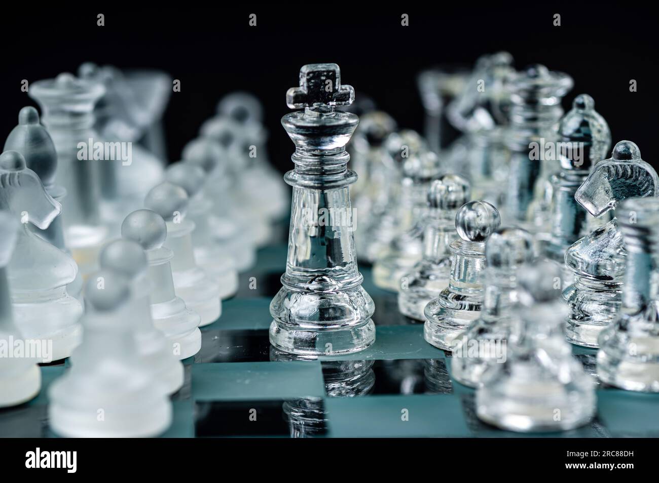 Pièces d'échecs en verre transparent sur fond sombre. Leadership, confrontation et concept de stratégie Banque D'Images