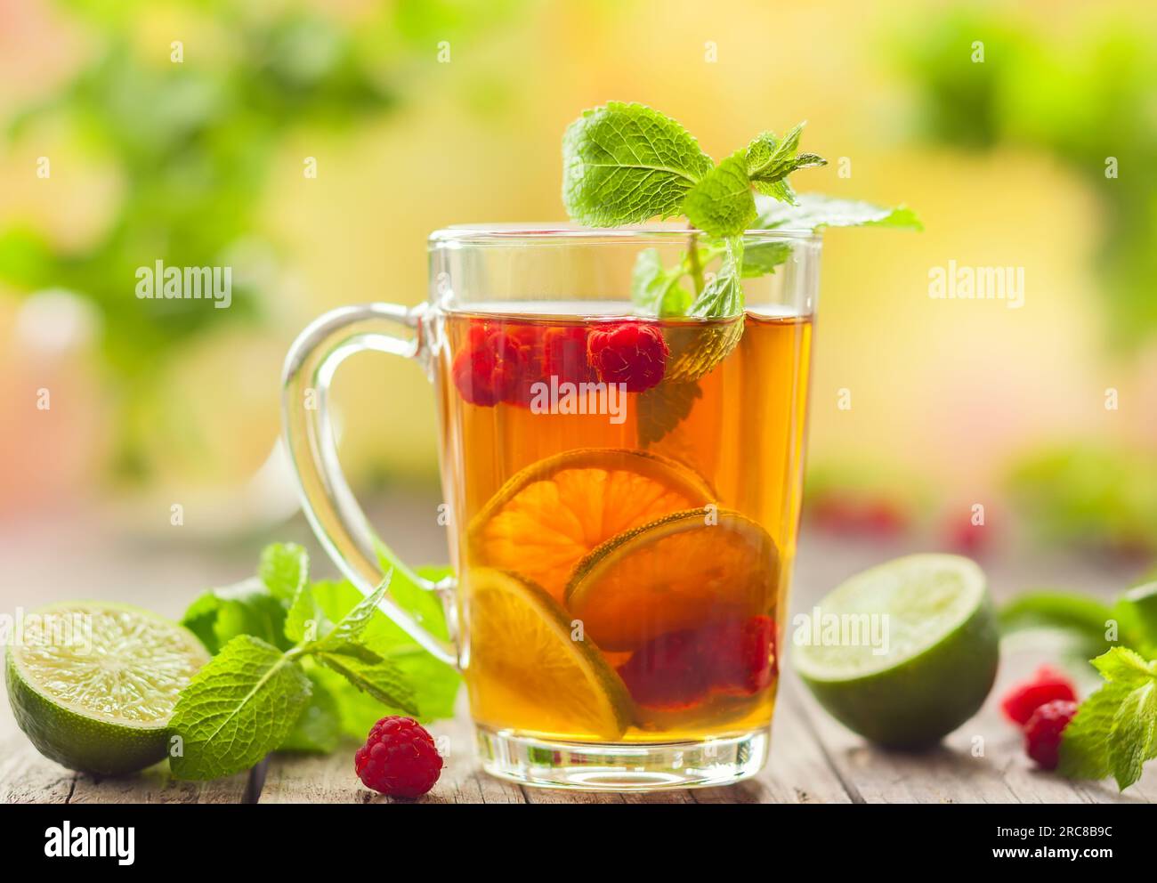 Verre de thé d'été avec framboises, citron vert et menthe sur table en bois Banque D'Images