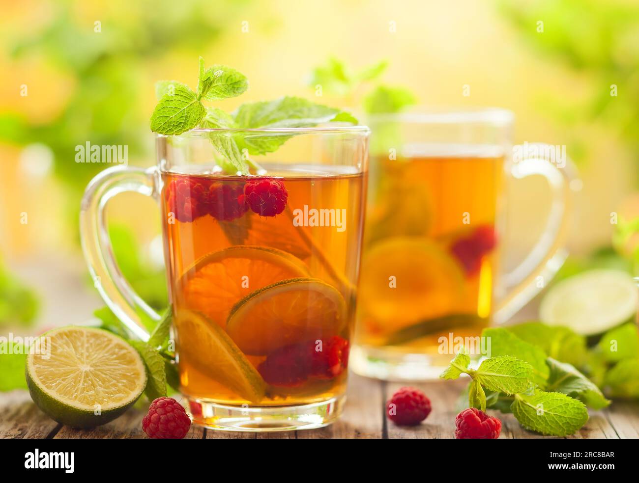 Verres de thé d'été avec framboises, citron vert et menthe sur table en bois Banque D'Images