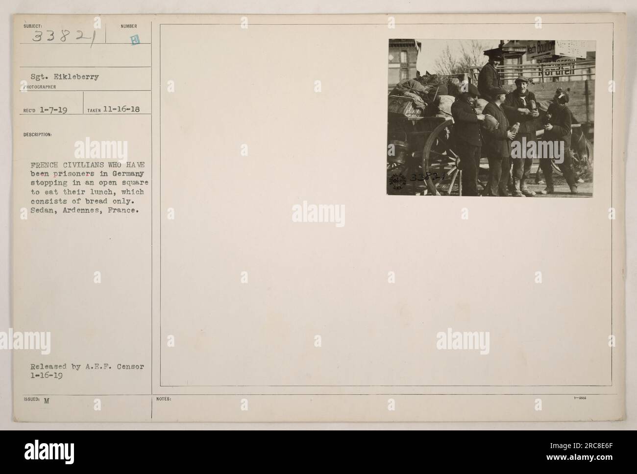 Des civils français qui étaient précédemment détenus comme prisonniers en Allemagne prenant une pause pour manger leur déjeuner sur une place ouverte. Le déjeuner se compose uniquement de pain. Cette photographie a été prise à Sedan, Ardennes, France. Il a été publié par A.R.F. Censurer le 16 janvier 1919. (Légende basée sur les informations fournies) Banque D'Images