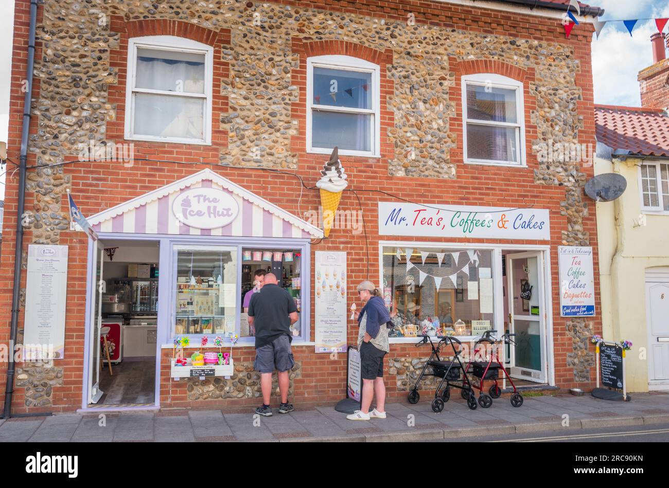 Clients du MR Tea's, Coffee's and Cake Shop et de l'Ice Hut sur la rue à Sheringham, Norfolh, Angleterre. Banque D'Images