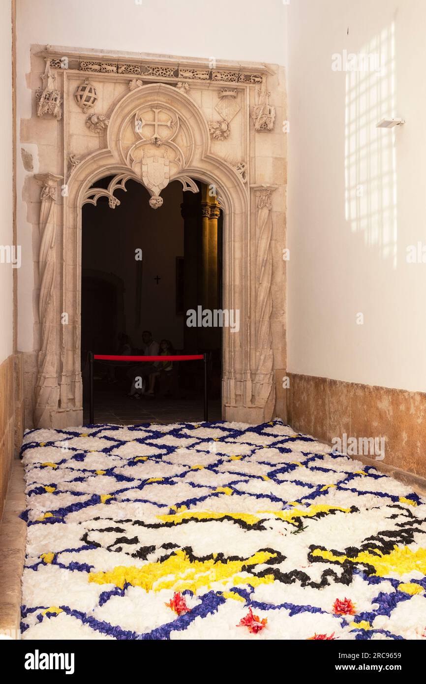 Tomar, Portugal - 8 juillet 2023 : Portail manuélin latéral de l'église de São João Baptista avec le sol décoré de fleurs en papier. Banque D'Images