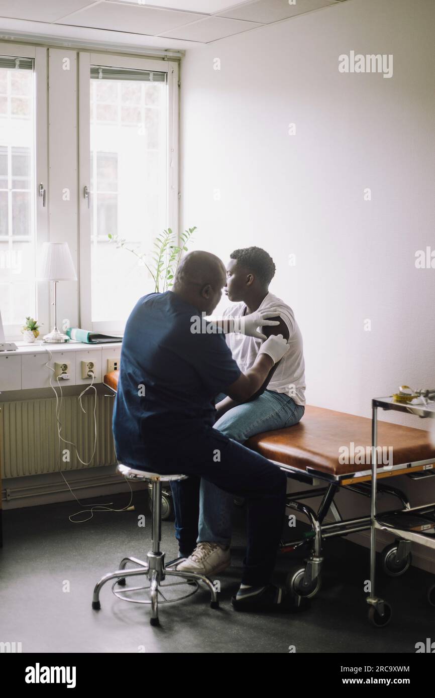 Médecin homme mature donnant la vaccination à un garçon à l'hôpital Banque D'Images