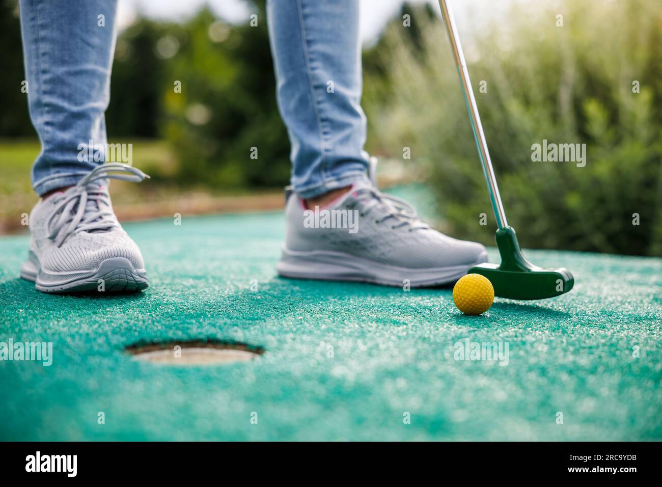 Golfeur jouant au mini-golf et essayant de mettre la balle dans le trou. Activités de loisirs estivales Banque D'Images