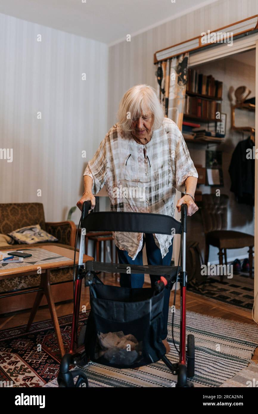Femme âgée marchant à la maison en utilisant la marchette de mobilité Banque D'Images