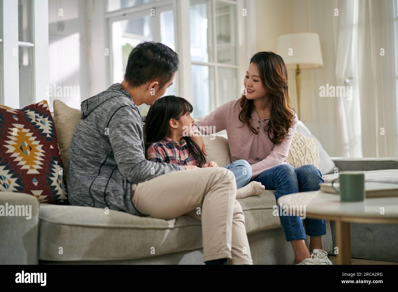 jeune mère asiatique et père assis sur le canapé de la famille à la maison ayant une conversation agréable avec sa fille Banque D'Images