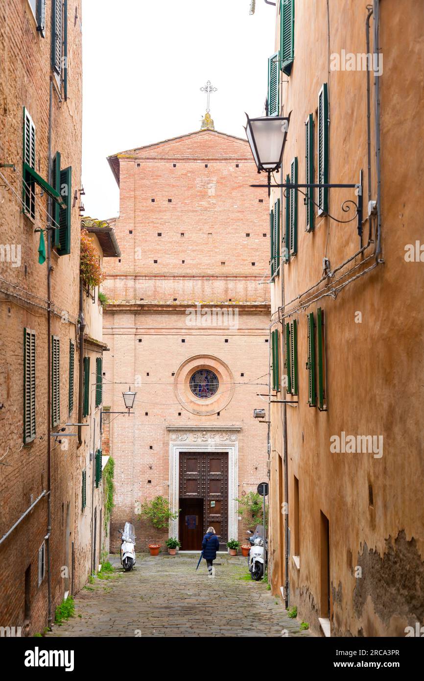 Sienne, Italie - APR 7, 2022: Petite église en brique et pierre et vue sur la rue depuis la ville italienne historique de Sienne en Toscane. Banque D'Images