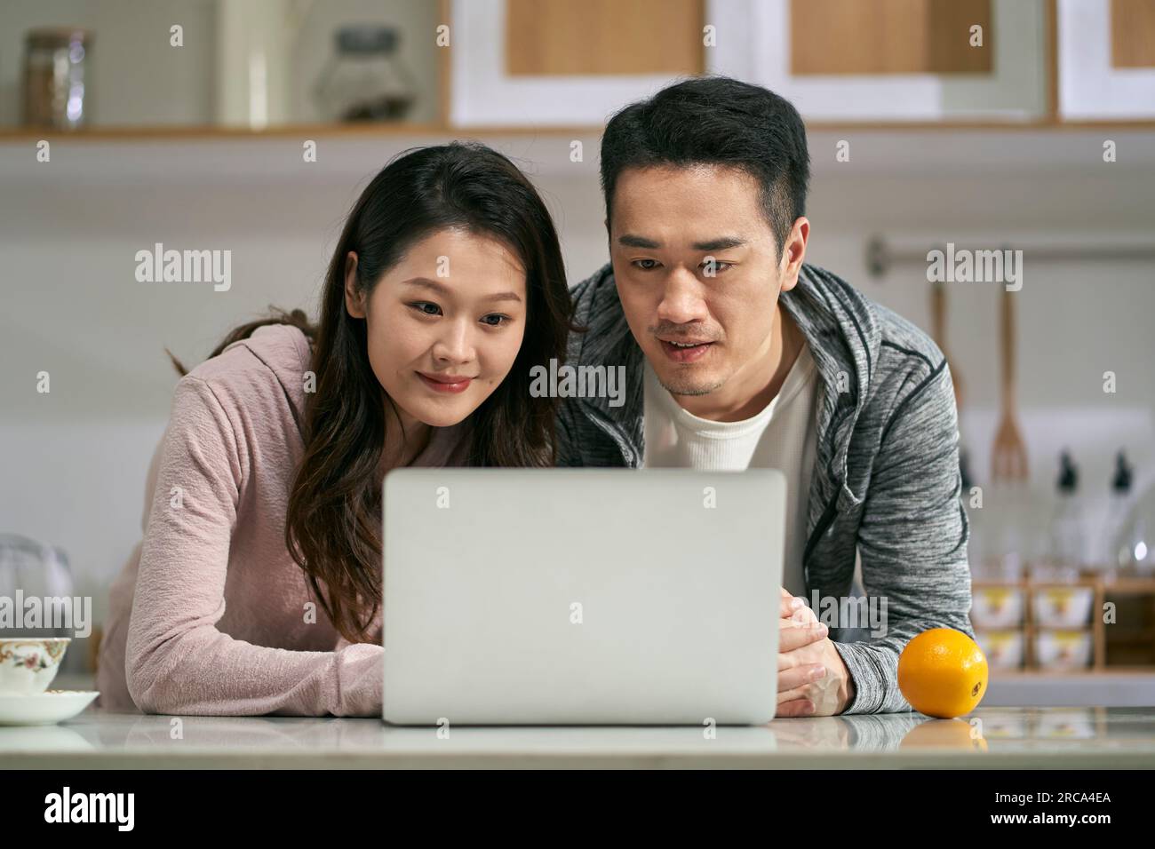 jeune couple asiatique utilisant un ordinateur portable ensemble dans la cuisine familiale à la maison Banque D'Images