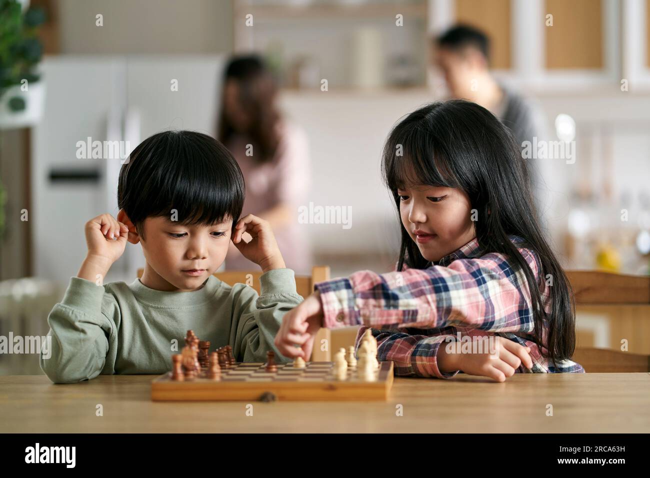 deux enfants asiatiques frère et sœur assis à table à la maison jouant aux échecs Banque D'Images
