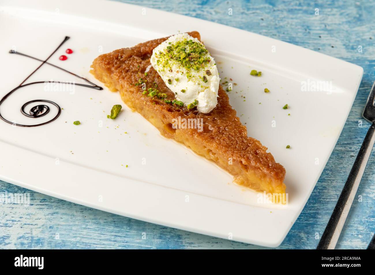 Dessert turc ekmek kadayifi avec crème de lait et pistache sur une assiette en porcelaine blanche Banque D'Images