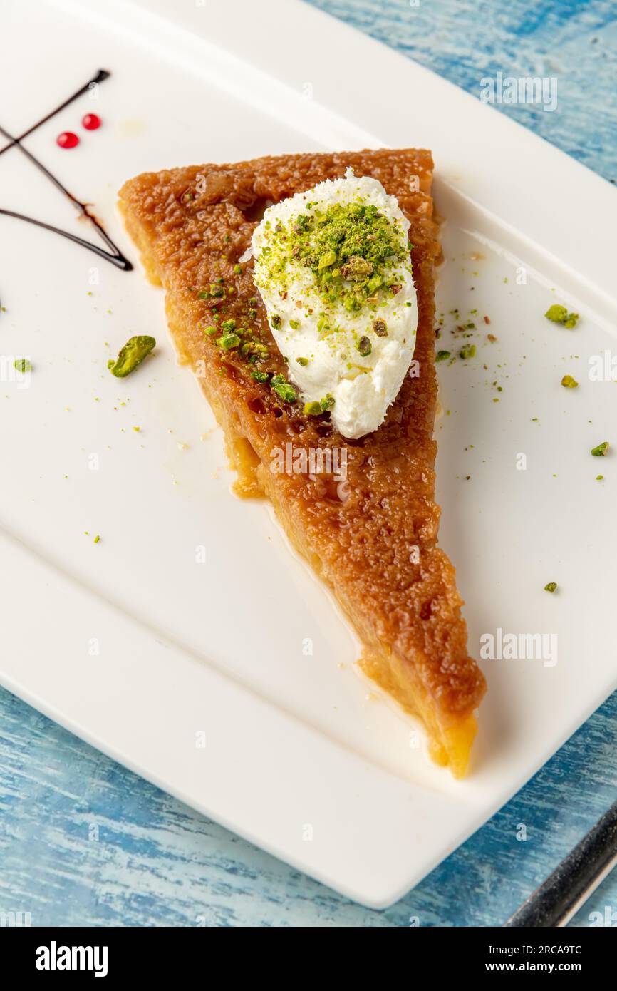 Dessert turc ekmek kadayifi avec crème de lait et pistache sur une assiette en porcelaine blanche Banque D'Images