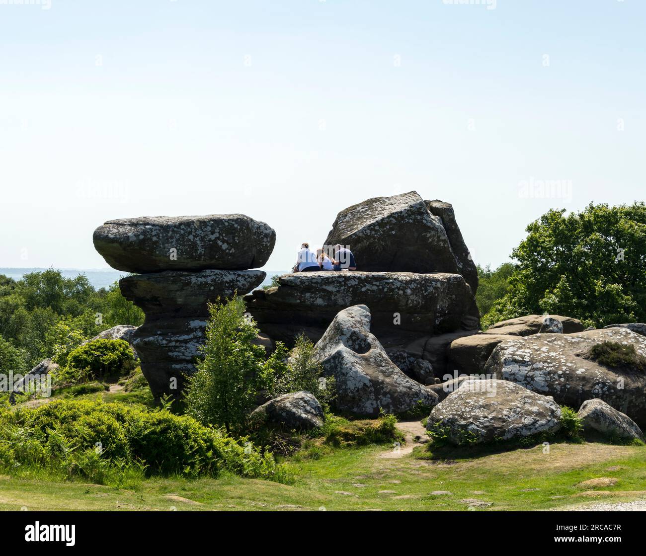 Famille reposant sur le rocher, Brimham Rocks, Harrogate, North Yorkshire, Angleterre, ROYAUME-UNI Banque D'Images