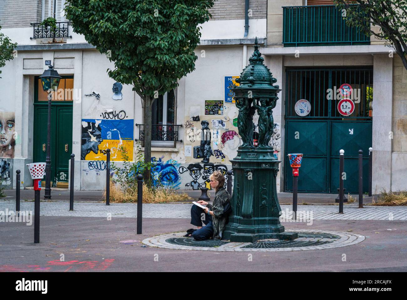 Femme assise à côté de la fontaine Wallace sur la place commune de Paris dans le populaire 13e arrondissement, Paris, France Banque D'Images