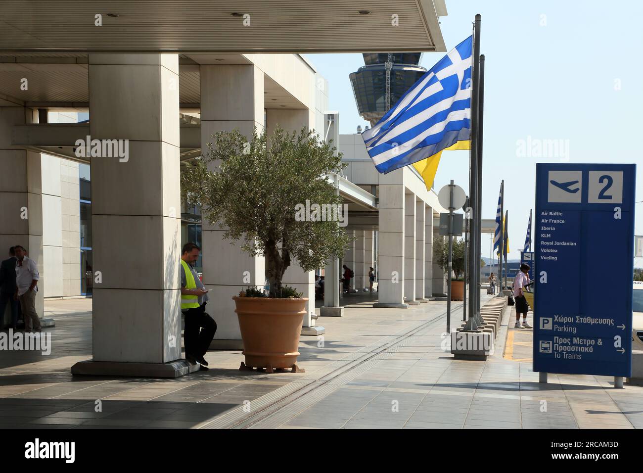 Athènes Grèce aéroport international d'Athènes (AIA) Eleftherios Venizelos Homme portant un gilet haute visibilité debout Olive Tree en pot à l'extérieur Banque D'Images