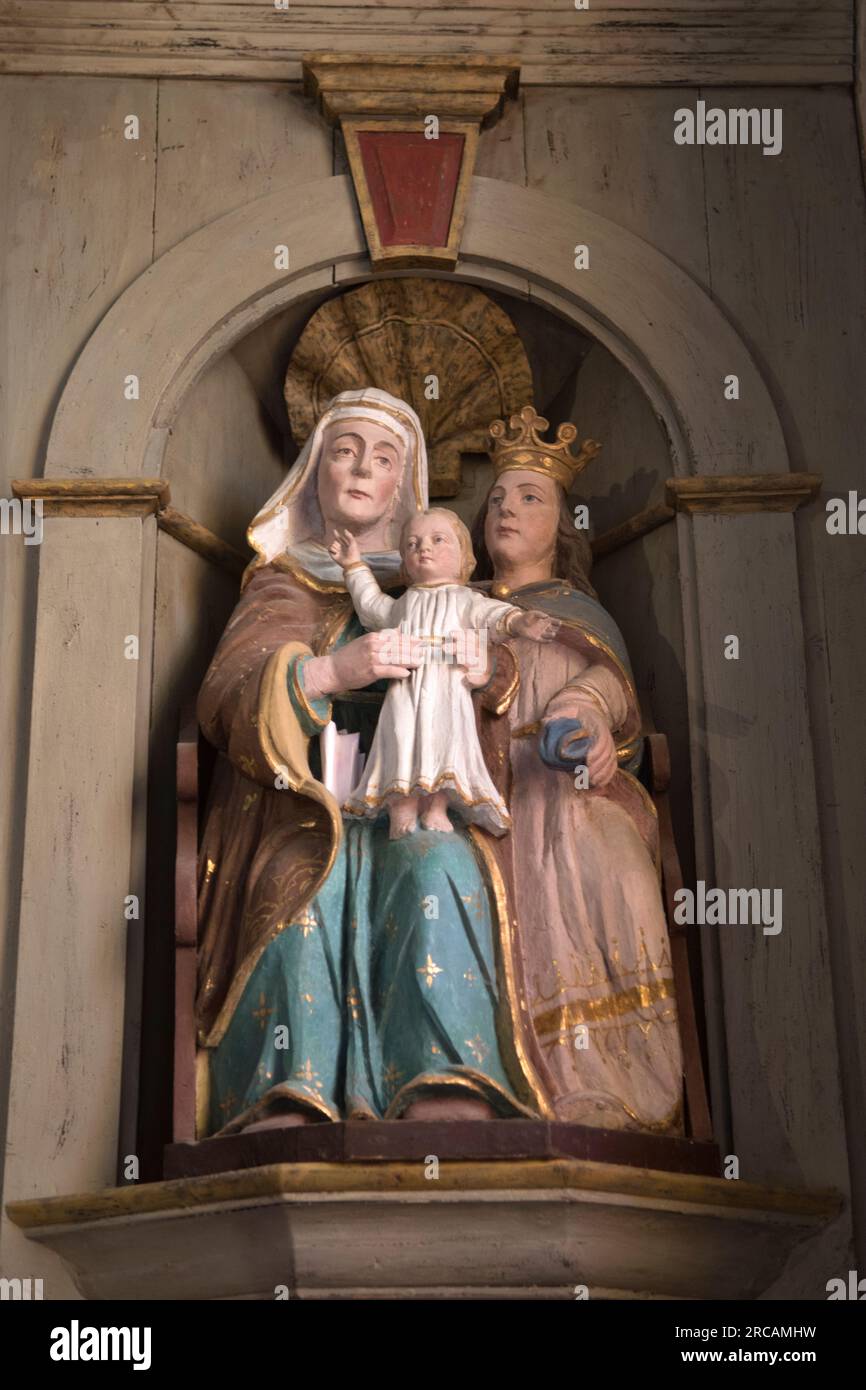 Sainte Anne grand-mère de Jésus, était la mère de Marie (ici portant une couronne.) Elle était la grand-mère maternelle de Jésus, vue tenant la silhouette du bébé Christ. Sculpture baroque française sur bois polychrome à l'église Saint Michel l'Archange. Saint Michel en Greve, Côtes-d'Armor, Bretagne, France. 10 juillet 2023 2020s HOMER SYKES Banque D'Images