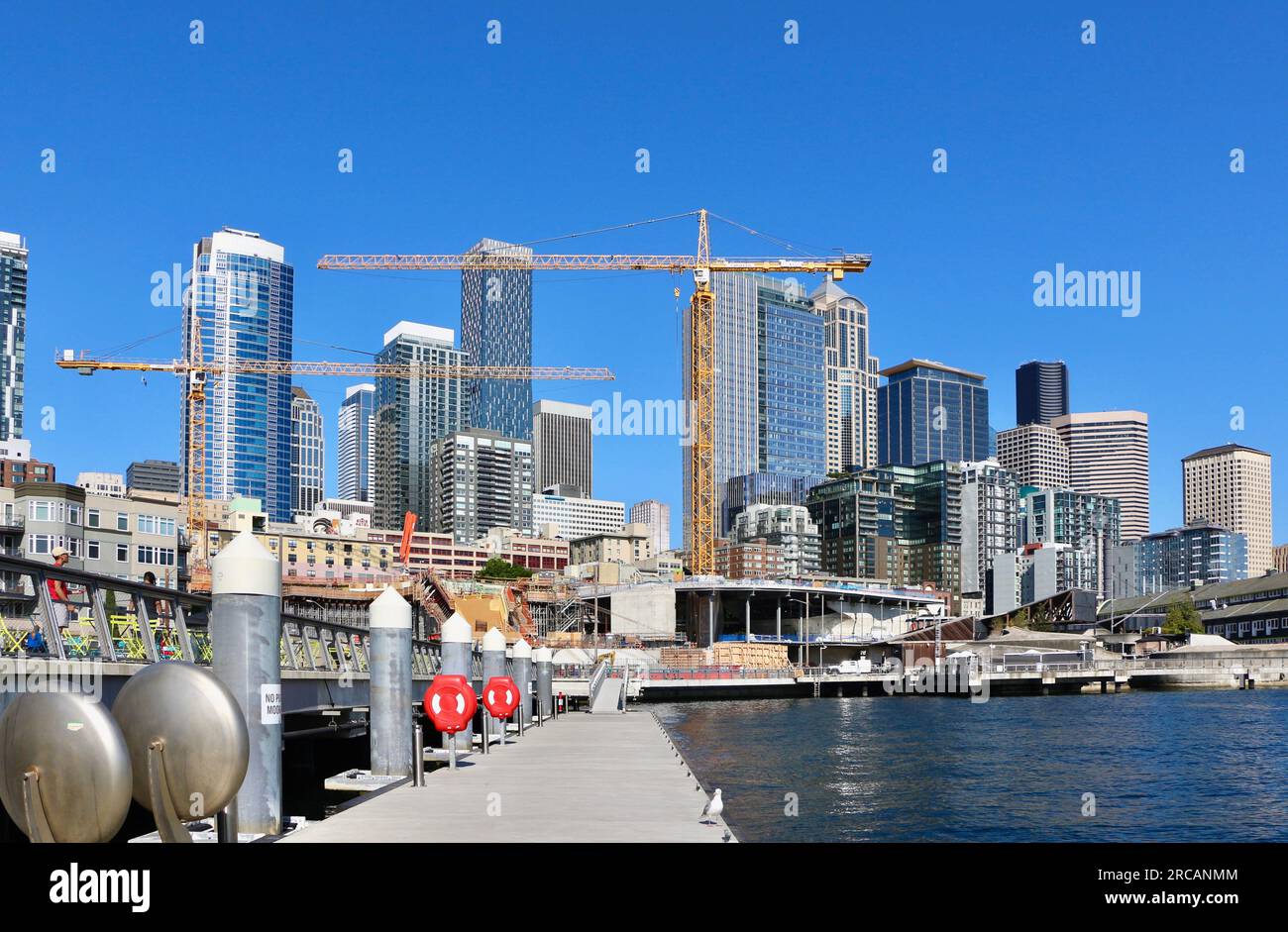Skyline de la ville avec un projet de construction et des grues à tour le long du front de mer à partir d'une jetée flottante Pier 62 Seattle Washington State USA Banque D'Images
