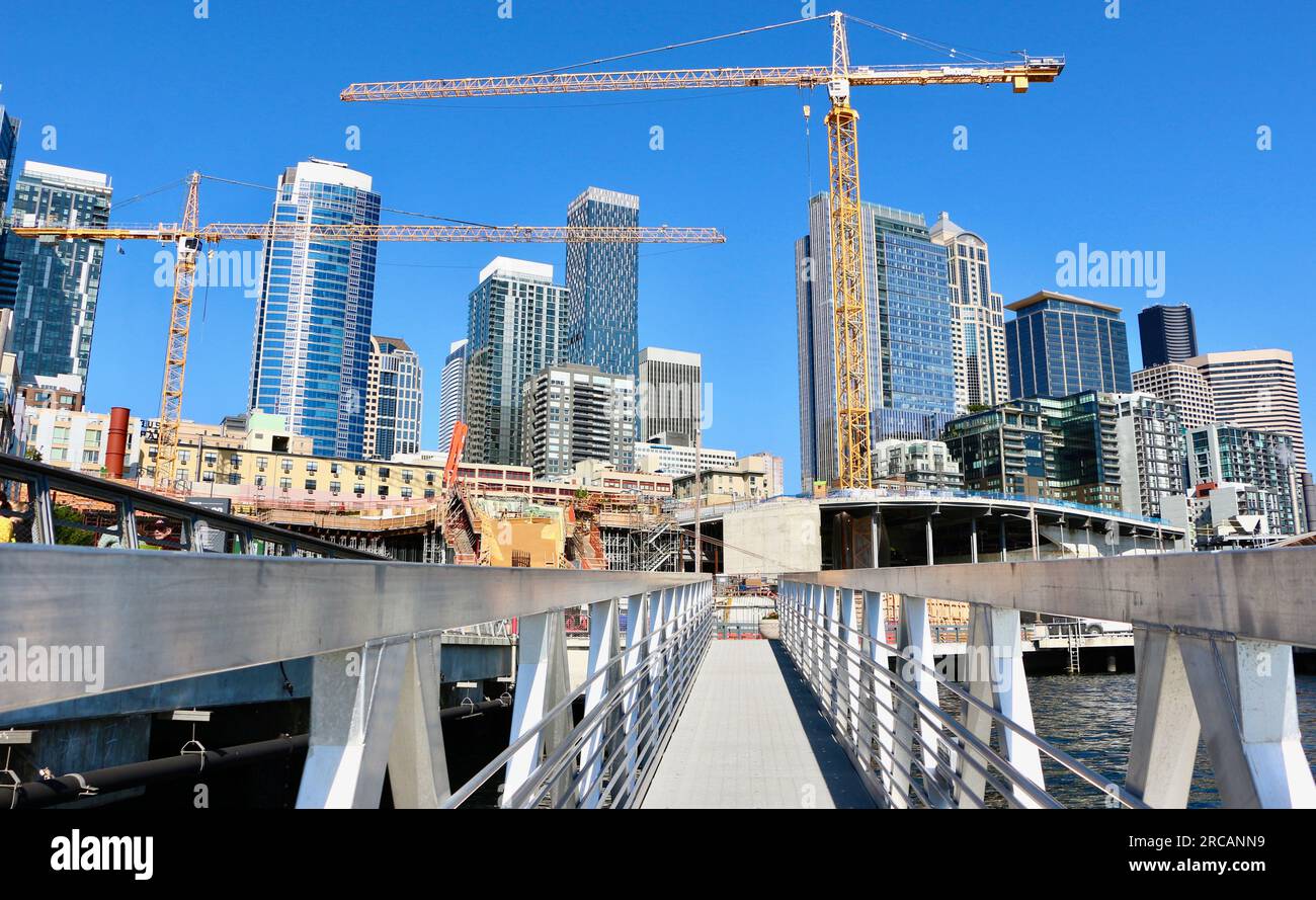 Skyline de la ville avec un projet de construction et des grues à tour le long du front de mer à partir d'une jetée flottante Pier 62 Seattle Washington State USA Banque D'Images