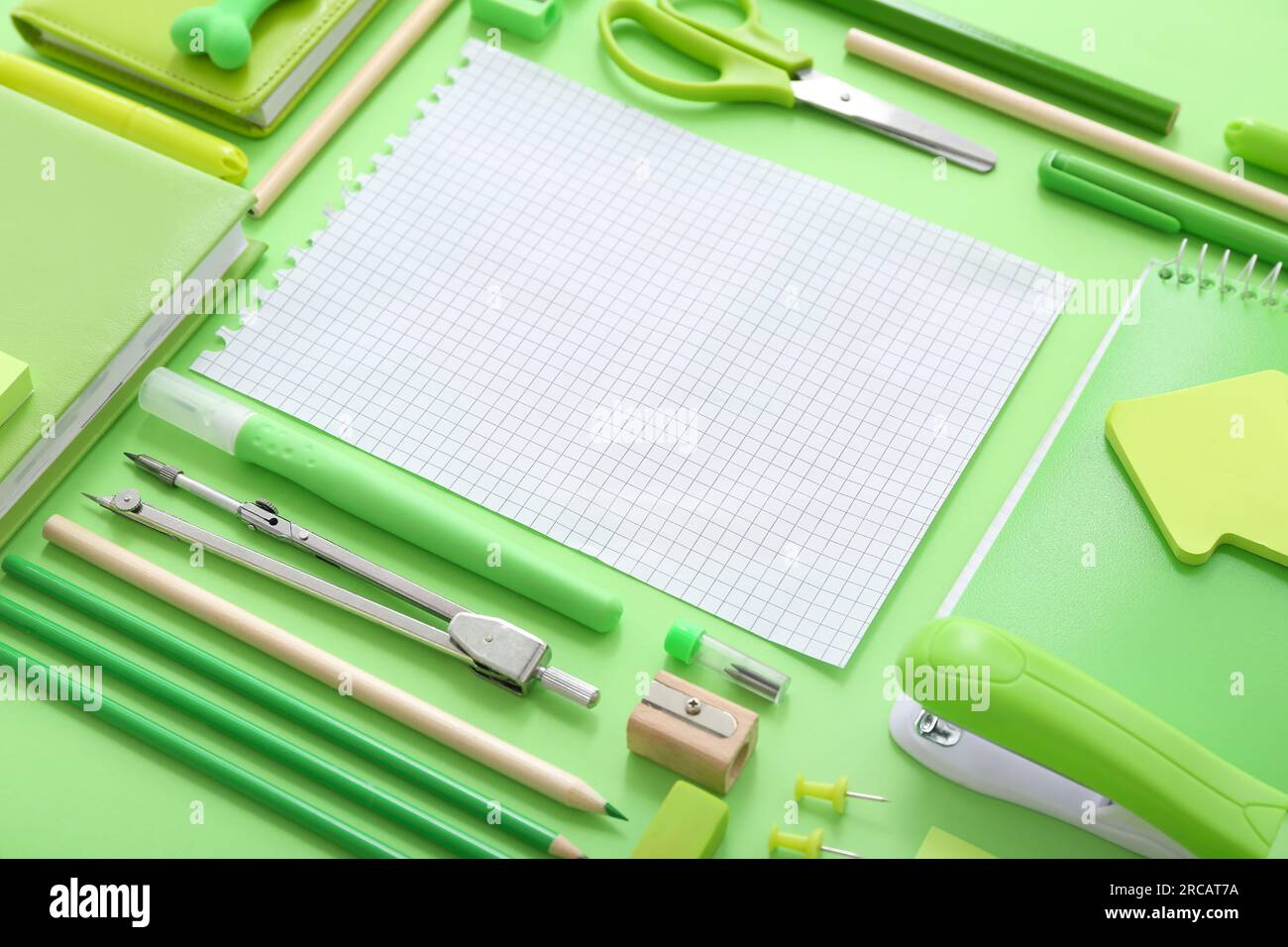 Bloc-notes vierge avec différents articles de papeterie sur fond vert Banque D'Images