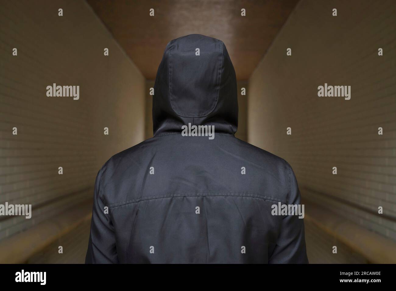 Un homme en noir dans un passage sombre. La vue de l'arrière. Criminalité et émeutes dans la rue Banque D'Images