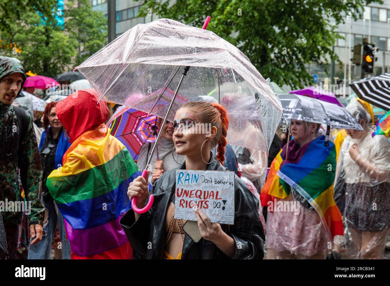 Jeune femme avec parapluie transparent et signe fait main à Helsinki Pride 2023 défilé un jour de pluie à Helsinki, Finlande Banque D'Images