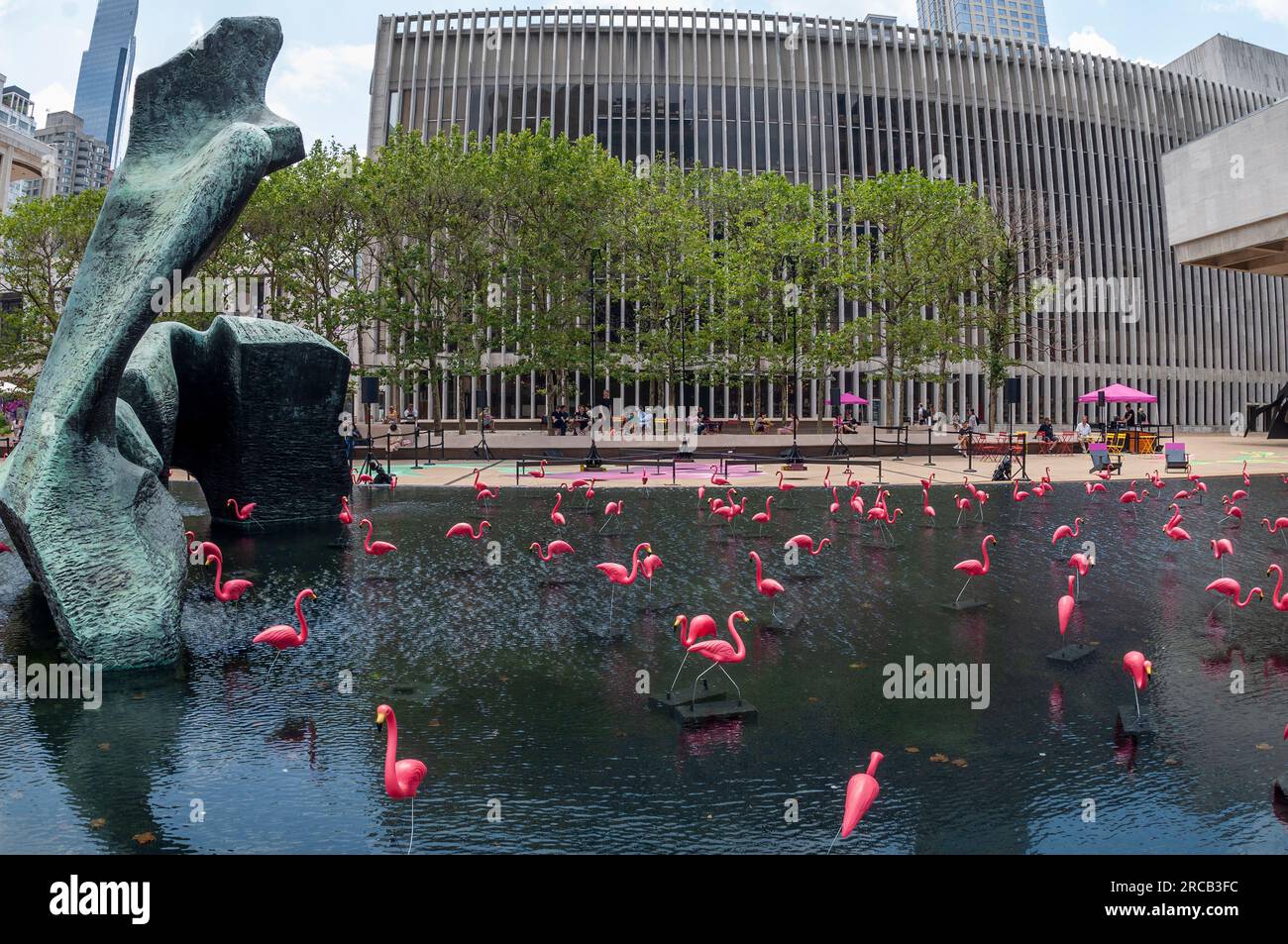 Les flamants roses partagent la piscine réfléchissante avec la « figure inclinable » de Henry Moore au Lincoln Center à New York le dimanche 2 juillet 2023. Le lieu des arts de la scène offre des centaines d'événements gratuits pendant leur festival Summer for the City. (© Richard B. Levine) Banque D'Images