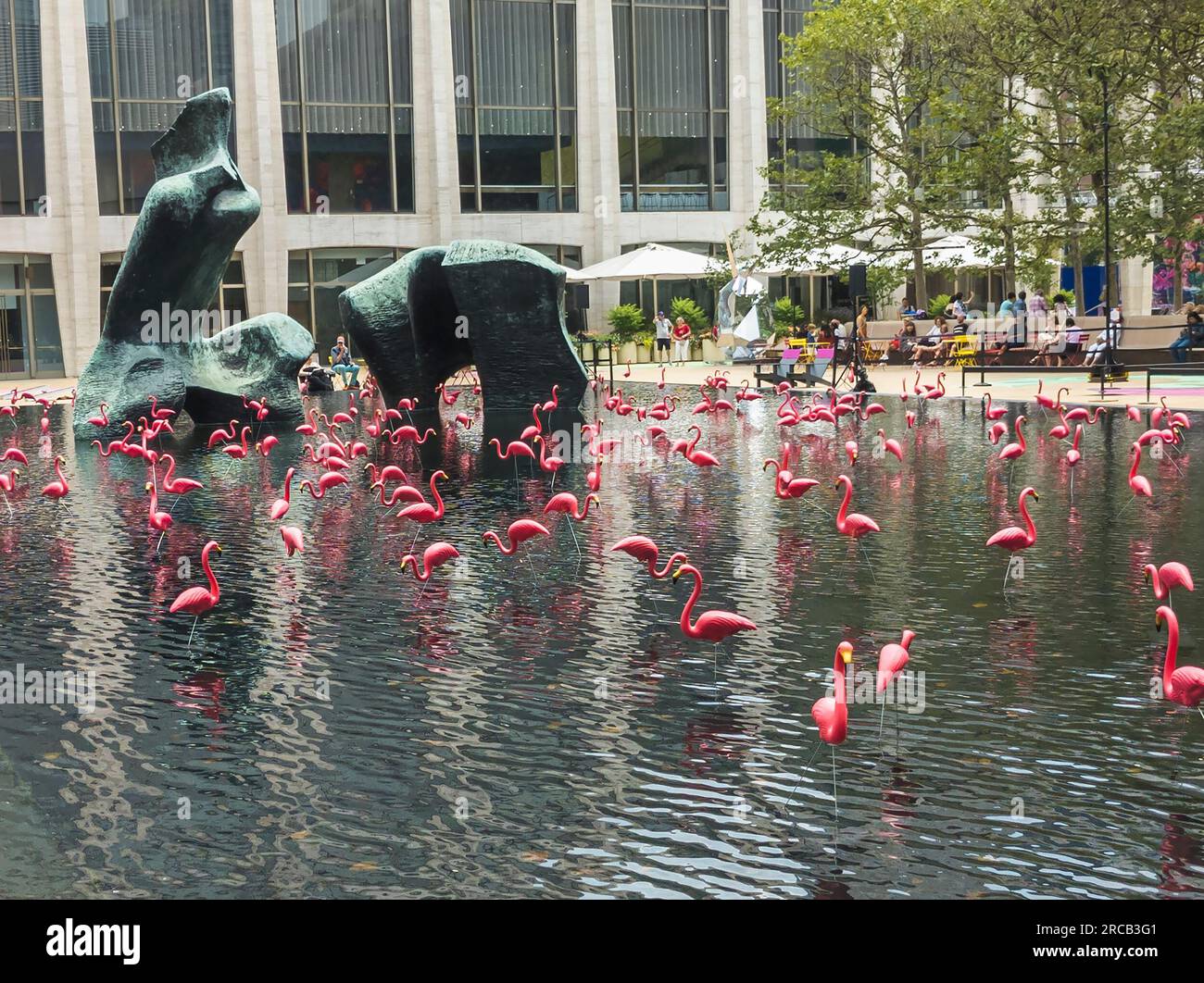 Les flamants roses partagent la piscine réfléchissante avec la « figure inclinable » de Henry Moore au Lincoln Center à New York le dimanche 2 juillet 2023. Le lieu des arts de la scène offre des centaines d'événements gratuits pendant leur festival Summer for the City. (© Richard B. Levine) Banque D'Images
